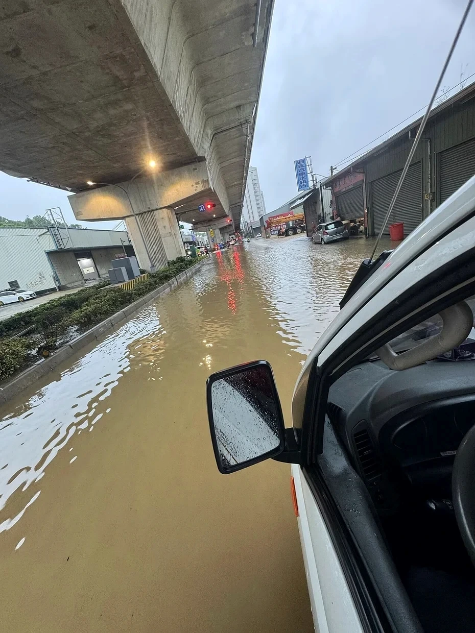 Muddy floodwater covering a road beneath an elevated structure in Kaohsiung