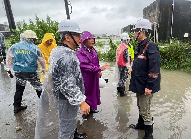 Kaohsiung Mayor Chen Chi-mai, wearing a purple raincoat, speaks with officials on a flooded road in Cieding District