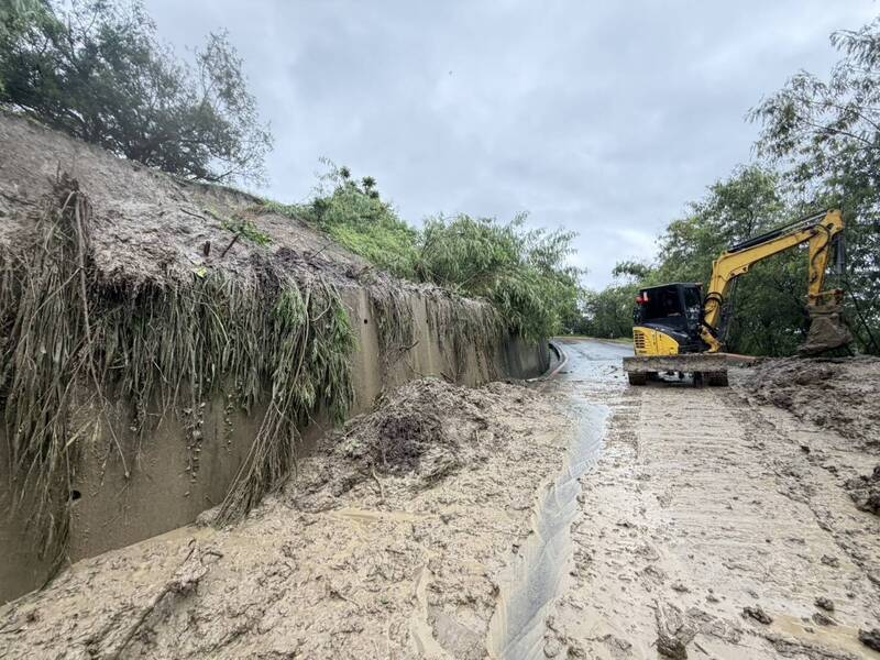 An excavator clearing mud and fallen earth from a road at Tianliao Moon World