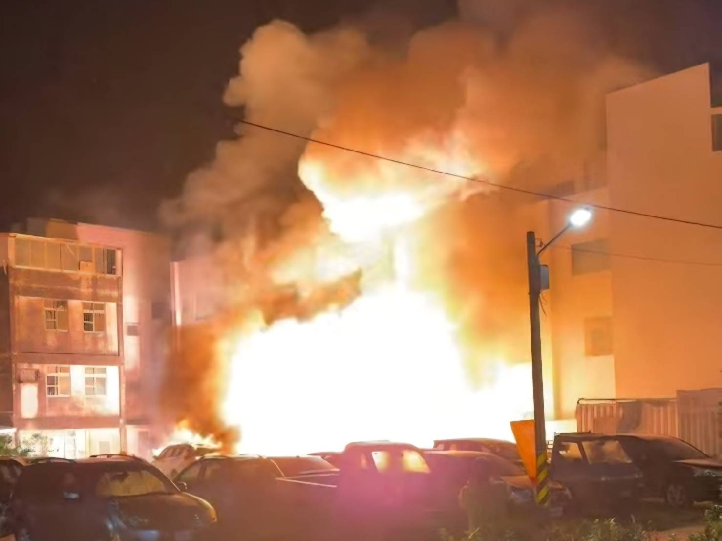 Flames and thick smoke rising between buildings during a nighttime fire in Tainan