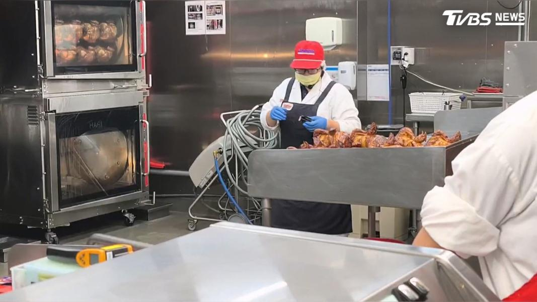 Worker beside rotisserie ovens and cooked chickens at Costco's Dashun warehouse in Kaohsiung