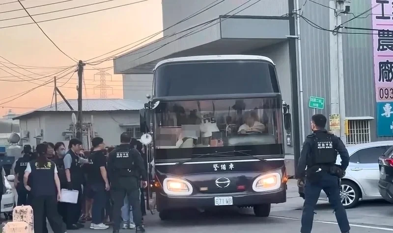 Police officers and a transport bus outside a building in Kaohsiung